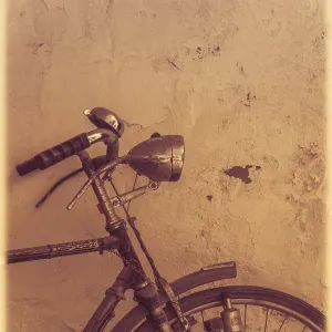 Old rusty vintage bicycle leaning against a wall in a countryside