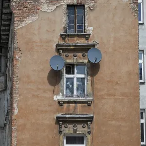 Old tenement house in poor condition with satellite dishes on the wall in Legnica