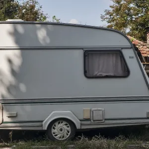 Old vintage caravan side view closeup at country house in sunny day Old vintage caravan side view closeup at country house in sunny day