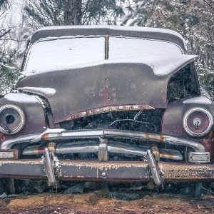 Old vintage plymouth automobile in the woods covered in snow Old vintage plymouth automobile in the woods covered in snow