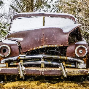 Old vintage plymouth automobile in the woods covered in snow Old vintage plymouth automobile in the woods covered in snow
