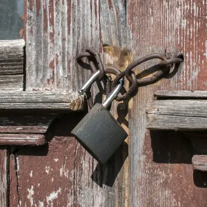 Old vintage weathered gunge locked padlock closeup on aged wooden door Old vintage weathered gunge locked padlock closeup on aged wooden door