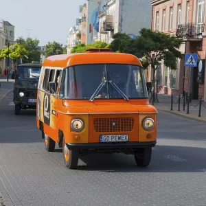 Orange bus drives through a sunny city street