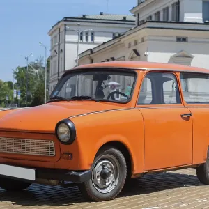 Orange colored vintage restored Trabant car on paved street Orange colored vintage restored Trabant car on paved street