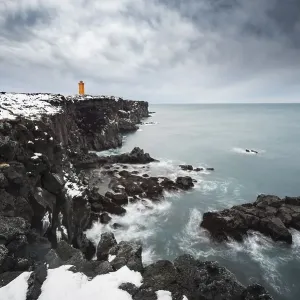Orange lighthouse Oendverdarnes stands on a dark cliff