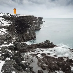 Orange lighthouse Oendverdarnes stands on a dark cliff