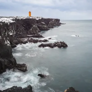 Orange lighthouse Ondverdarnes stands on a dark cliff