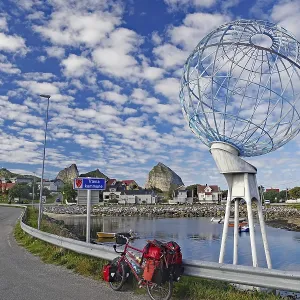 Packed touring bike in front of a huge globe and a harbour Packed touring bike in front of a huge globe and a harbour