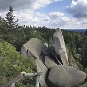 Panoramic view of a mountain landscape with rocks and trees under a dramatic sky
