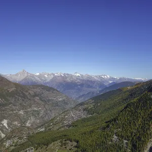 Panoramic view of a valley with mountains and forest under a clear sky
