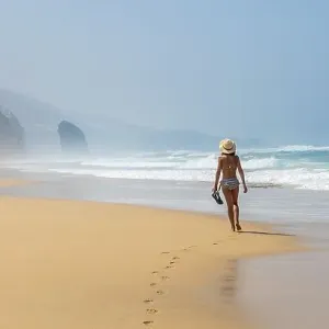 Panoramic of a young tourist with a hat walking alone on the Cofete beach of the Jandia natural park Panoramic of a young tourist with a hat walking alone on the Cofete beach of the Jandia natural park