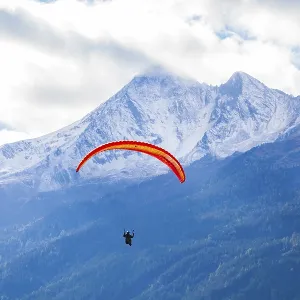 Paraglider and snowy Brennerspitze mountain in autumn