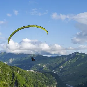 A paraglider in a vast mountain landscape with blue sky and white clouds A paraglider in a vast mountain landscape with blue sky and white clouds