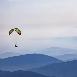 Paragliders high above the mountains with a view of the Klagenfurt basin and the Karawanken