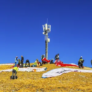 Paragliders prepare for takeoff below the transmitter and cell phone tower Paragliders prepare for takeoff below the transmitter and cell phone tower