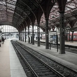 Passengers at a train station with red trains and arched architecture in Copenhagen Passengers at a train station with red trains and arched architecture in Copenhagen