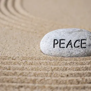 Peace text engraved on Zen stone on sand