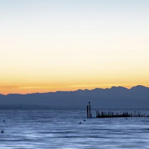 Peaceful mornings at the lake with soft colors and mountain silhouettes