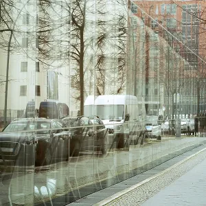 Pedestrian pathway with walking people along huge glass wall in Berlin city by late autumn Pedestrian pathway with walking people along huge glass wall in Berlin city by late autumn
