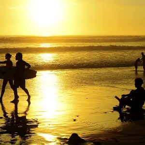 People on the beach with surfboard at sunset