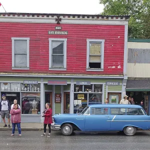 People and classic cars in front of a historic facade