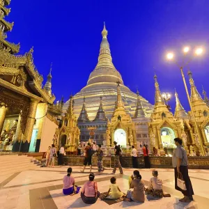 People gather in front of illuminated stupas in a temple-like setting at night