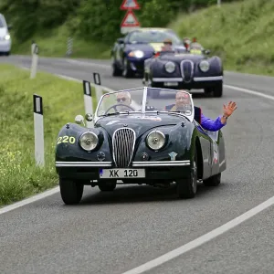Two people in a green vintage convertible on a winding country road Two people in a green vintage convertible on a winding country road