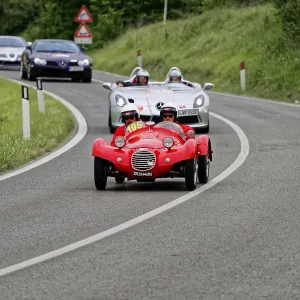 Two people with helmets in a red classic car on a country road Two people with helmets in a red classic car on a country road