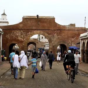 People walk through a historic stone gate in the souk of Essaouira