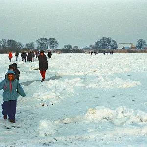 People walk across ice rink, frozen Elbe