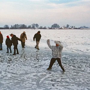 People walk across ice rink, frozen Elbe People walk across ice rink, frozen Elbe