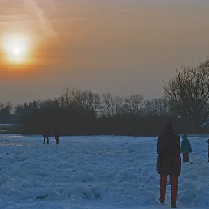People walk across ice rink, sunset