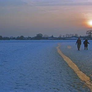 People walk across ice rink, sunset