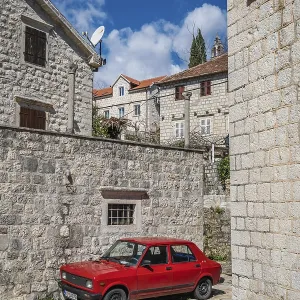 Perast, Montenegro - April 2018 : Old red retro vintage car in Perast town in the Kotor Bay Perast, Montenegro - April 2018 : Old red retro vintage car in Perast town in the Kotor Bay