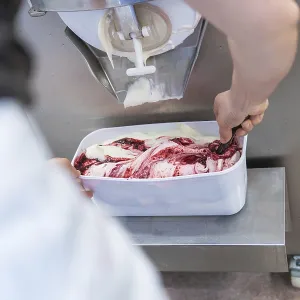 A person packing fruit ice cream in a white container