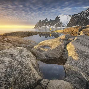Person with yellow jacket standing on the rocky beach of Tungeneset