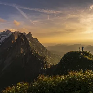 Photographer on grassy ridge at sunset with Santis peak in the background