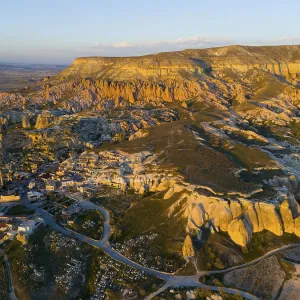 A picturesque landscape with rock formations and a small village in warm sunset light