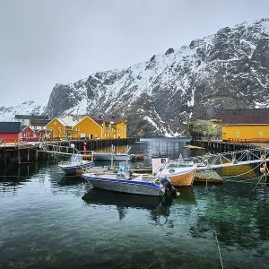 Pier with boats in Nusfjord authentic fishing village in winter with red rorbu houses Pier with boats in Nusfjord authentic fishing village in winter with red rorbu houses