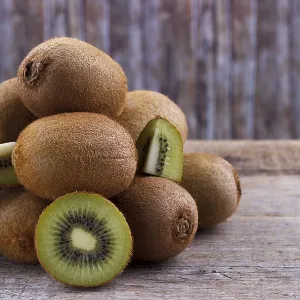 Pile of fresh kiwi on an old wooden board Pile of fresh kiwi on an old wooden board