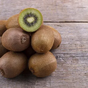 Pile of fresh kiwi on an old wooden board Pile of fresh kiwi on an old wooden board