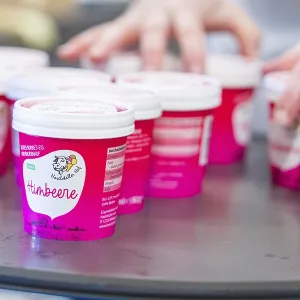 Several pink cups of raspberry ice cream are ready on a table