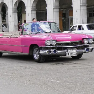 A pink vintage convertible in the midst of urban traffic shows retro charm on the street A pink vintage convertible in the midst of urban traffic shows retro charm on the street
