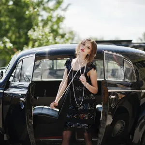 Portrait of beautiful sexy curly fashion girl model with bright makeup in retro style near vintage car