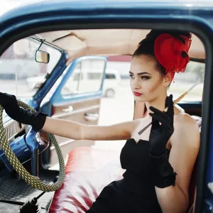 Portrait of beautiful sexy fashion girl model with bright makeup in retro style sitting in vintage car with a cigarette