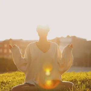 Portrait of young millenial european short haired woman doing yoga lotus asana on green grass meadow summer park sunset Portrait of young millenial european short haired woman doing yoga lotus asana on green grass meadow summer park sunset