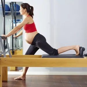 Pregnant woman pilates reformer cadillac exercise workout at gym