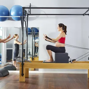 Pregnant woman pilates reformer short box exercise workout with personal trainer