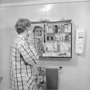 Preparing for a shave: A man stands in front of a bathroom mirror in his pyjamas