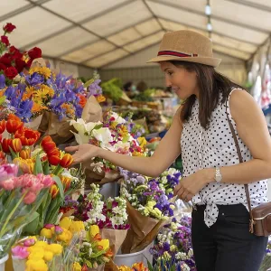 A pretty tourist with a photo camera visiting a flower market